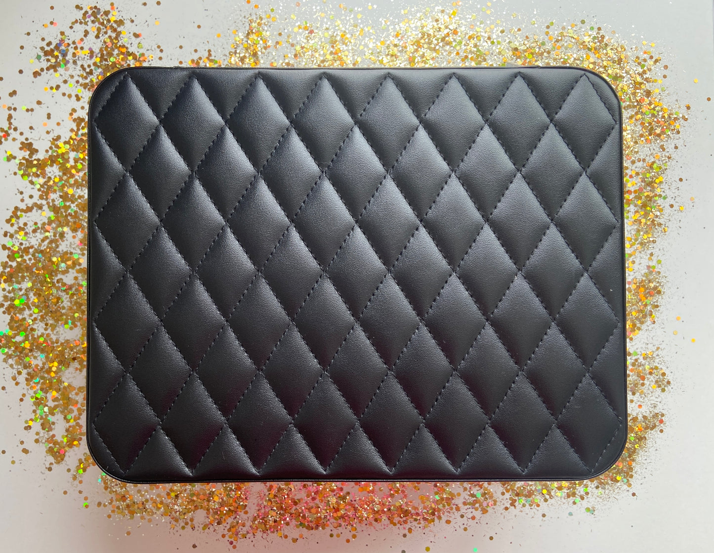 Black Jewelry box on a glittery surface with a white background