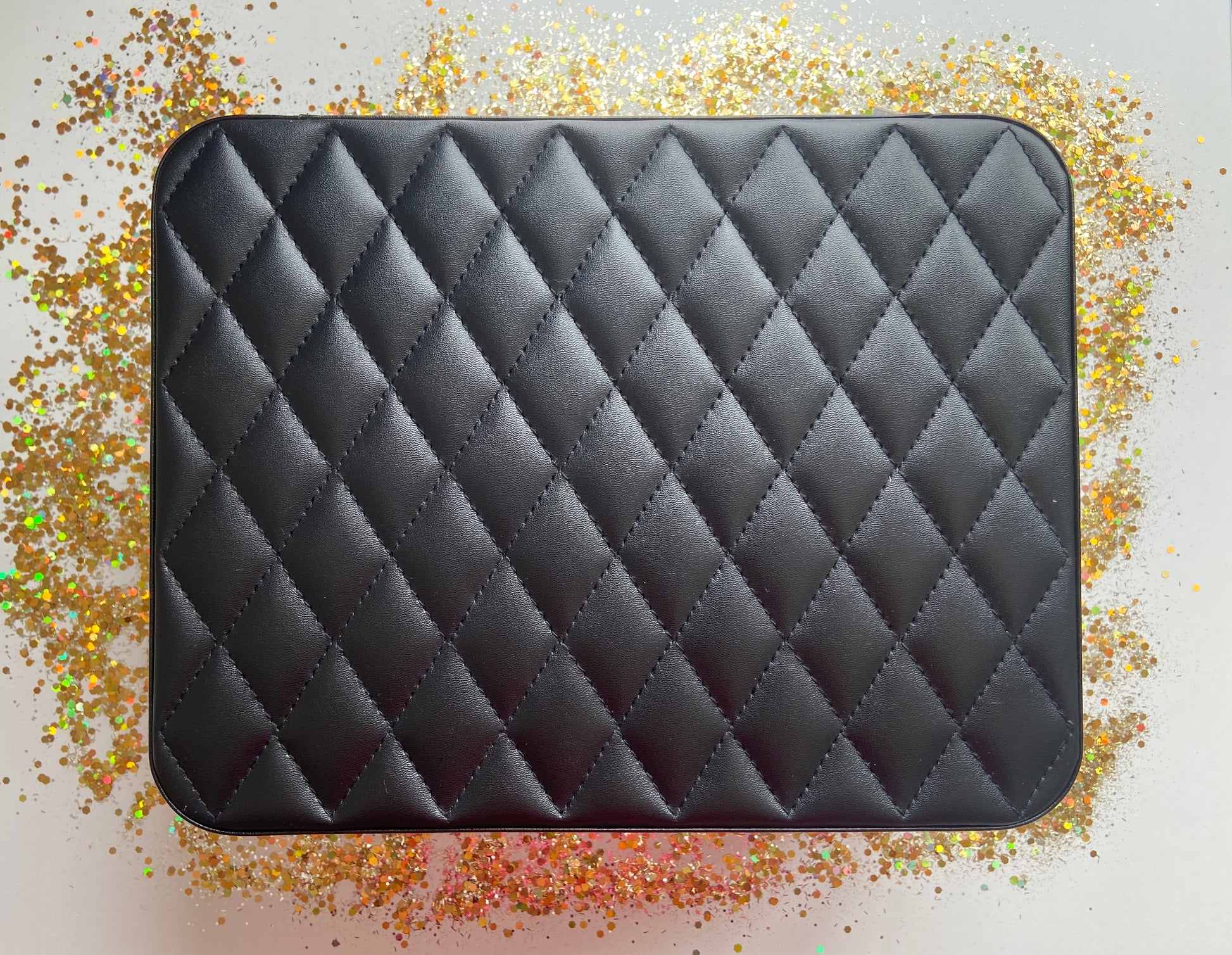 Black Jewelry box on a glittery surface with a white background